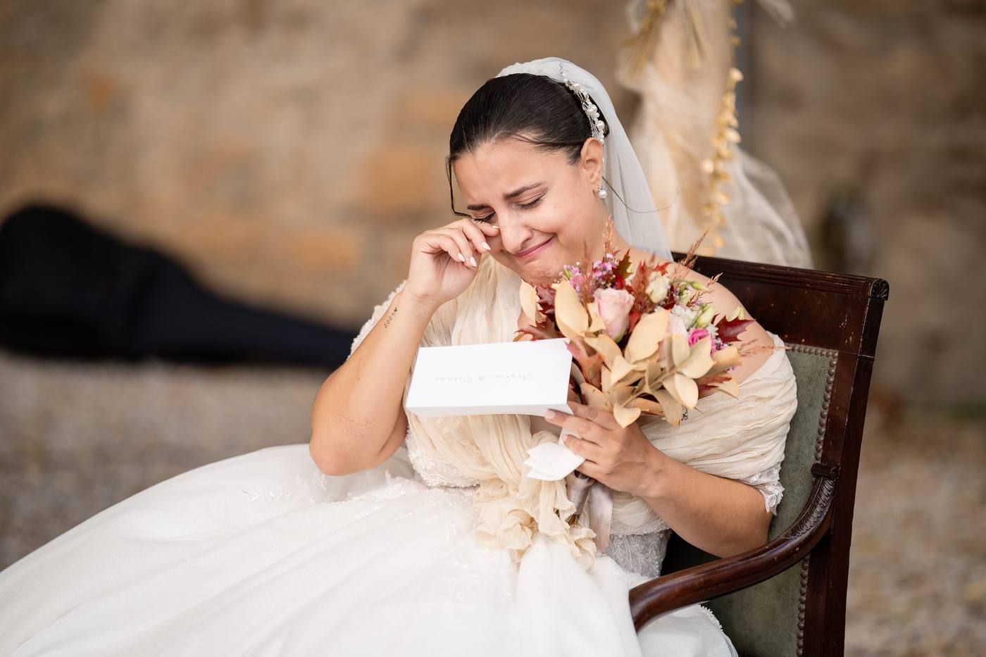 La mariée essuie une larme pendant la cérémonie, bouquet de fleurs séchées à la main